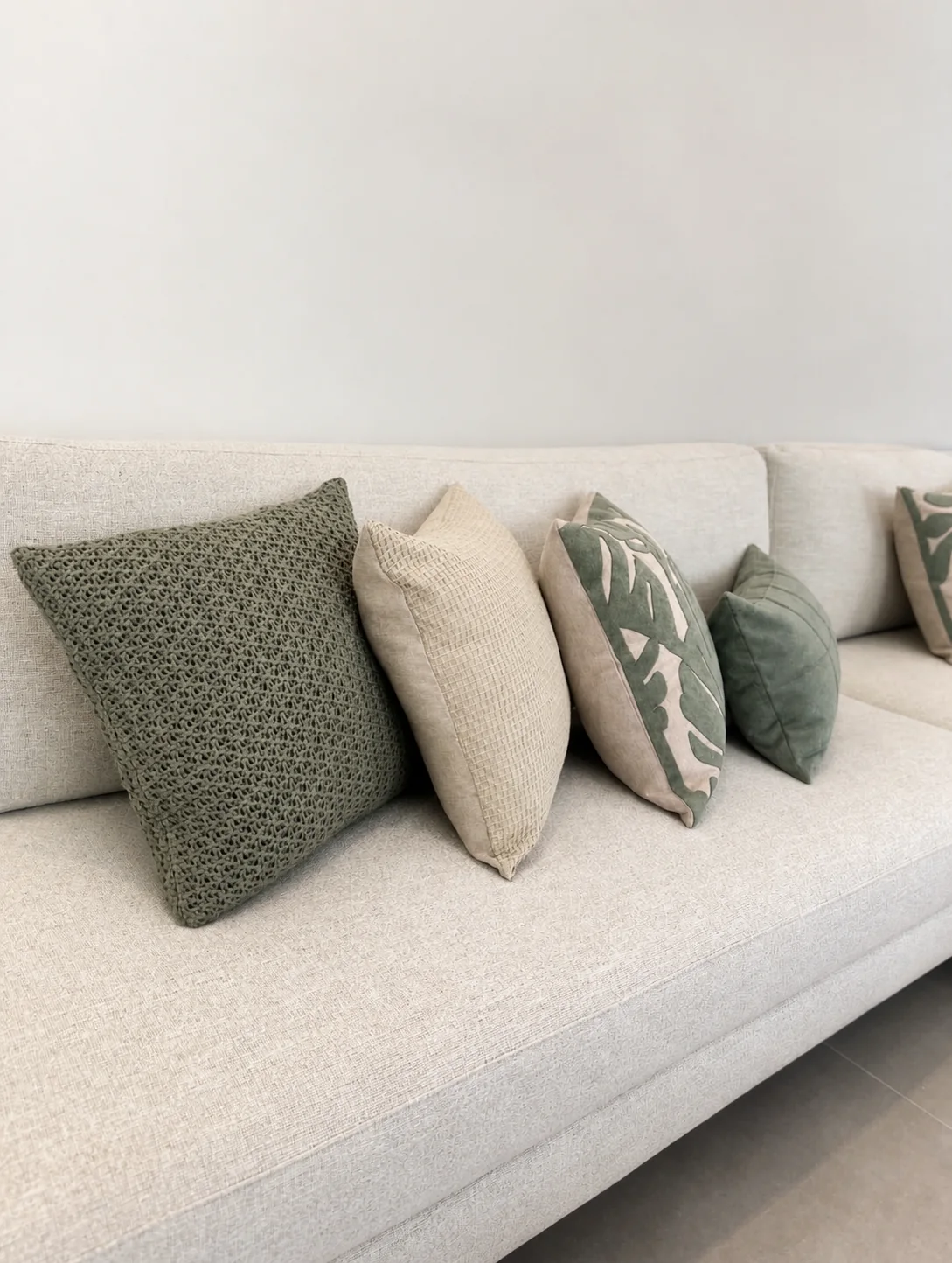 Almofadas decorativas em diferentes texturas sobre sofá de linho claro