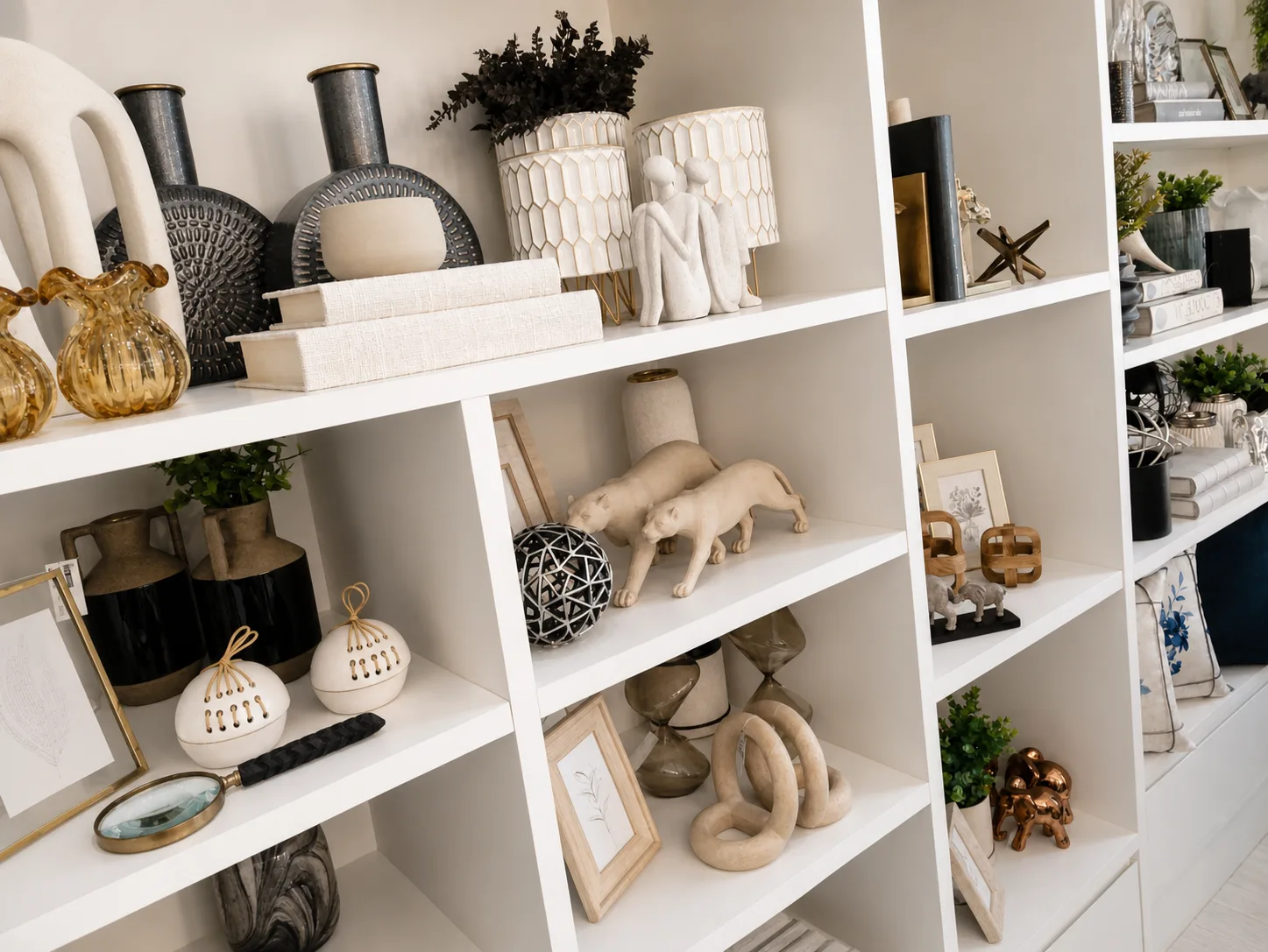 Estante branca com vasos, cerâmicas, livros e objetos decorativos