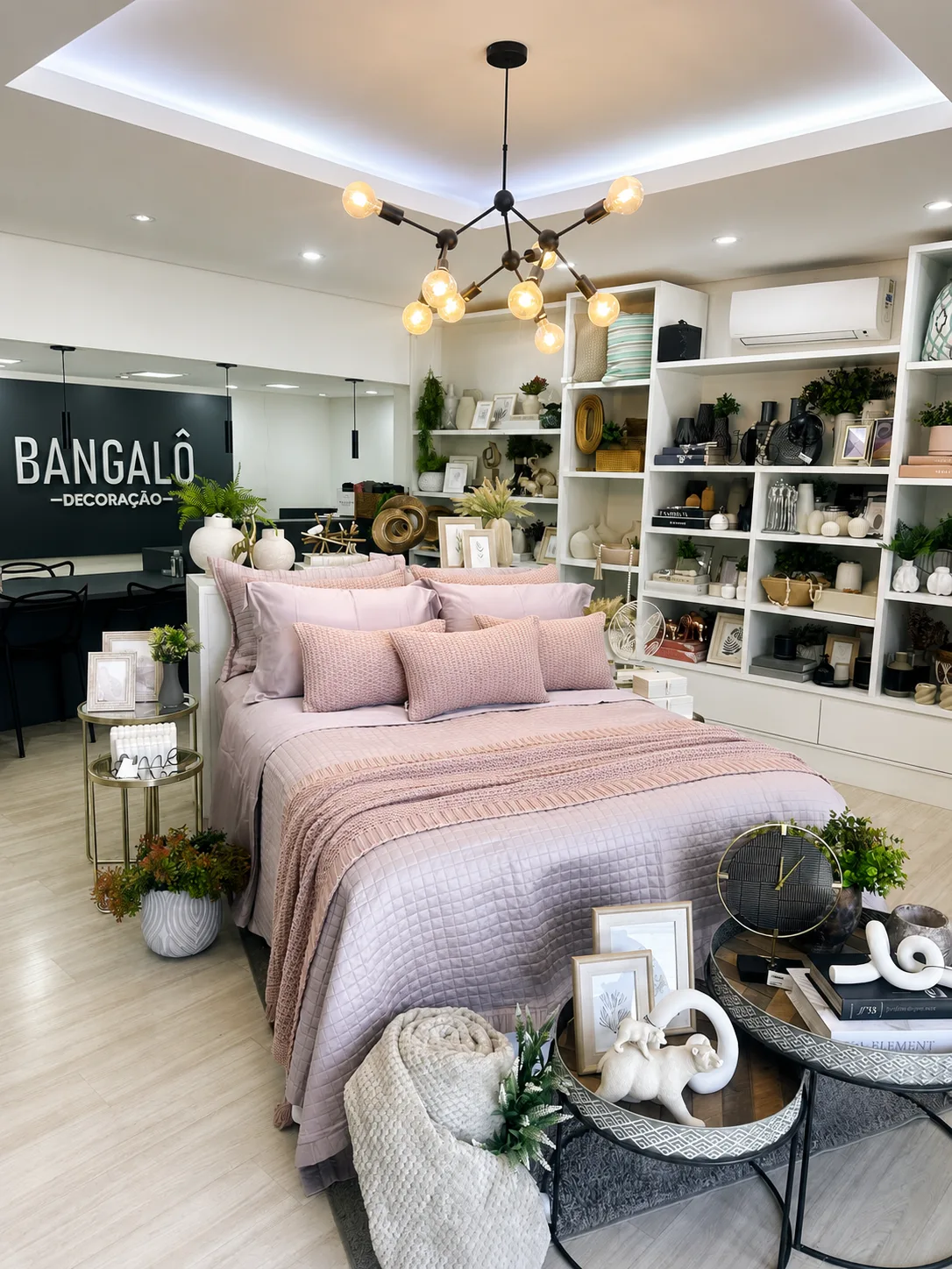 Cama montada com colcha, peseira e almofadas no showroom da Bangalô Decoração em Campinas
